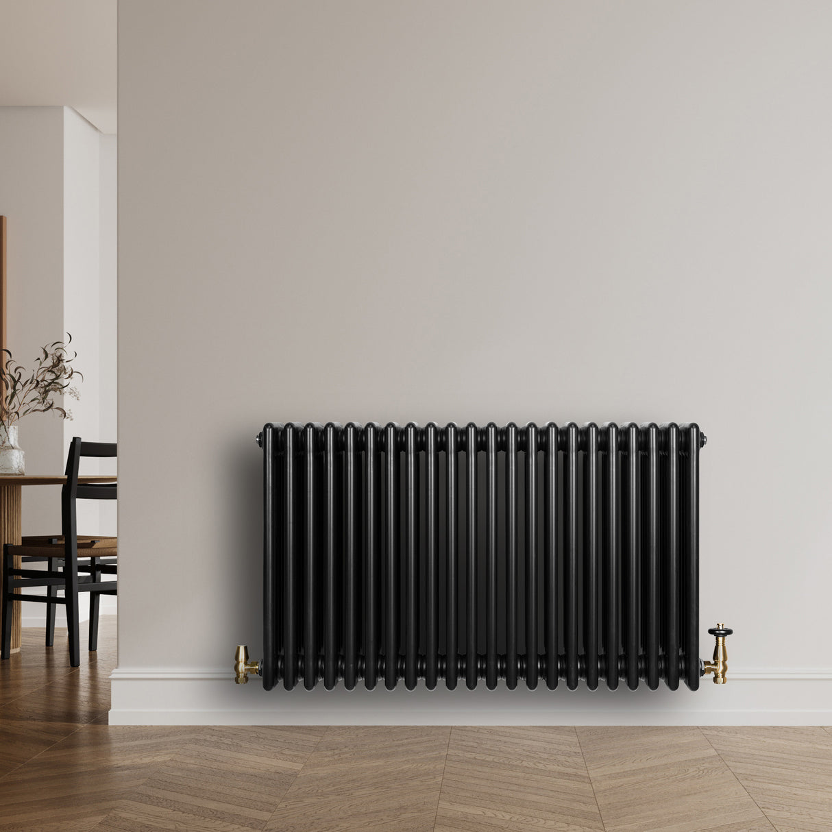 Radiatore tradizionale orizzontale a 4 colonne, finitura nera lucida, installato su parete bianca con valvole dorate, design elegante e moderno
