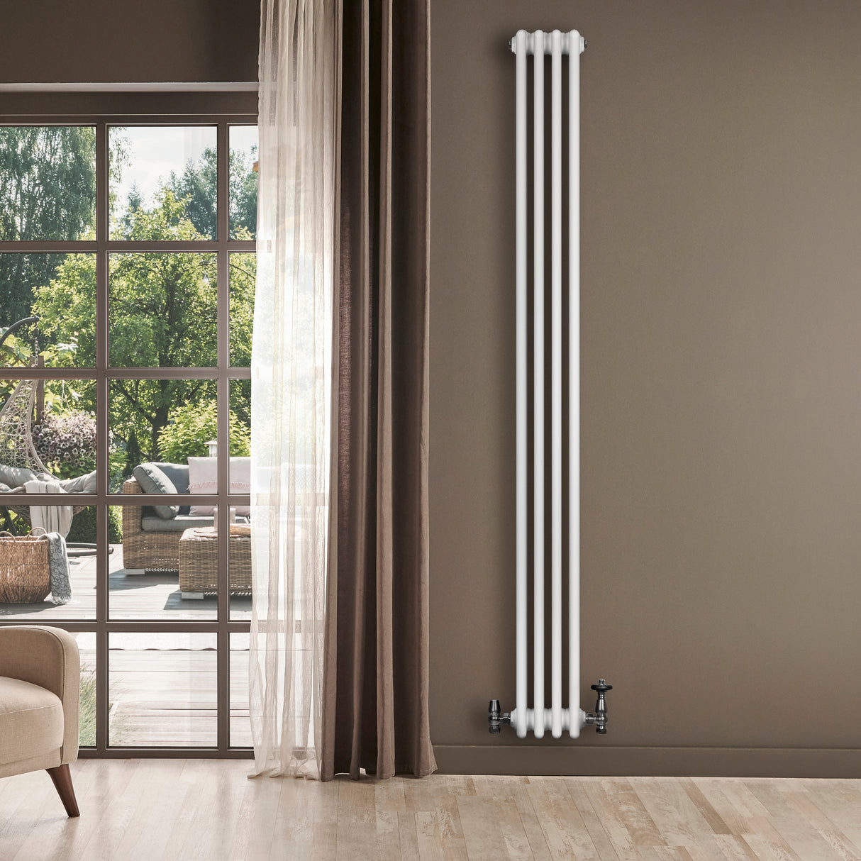 Radiatore tradizionale verticale a 4 colonne, finitura bianca, installato su parete beige, con valvole e vista su un giardino luminoso
