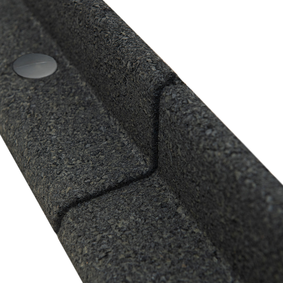 Vassoio in materiale riciclato grigio scuro, con texture ruvida e angoli smussati, dotato di un pulsante nero sulla superficie