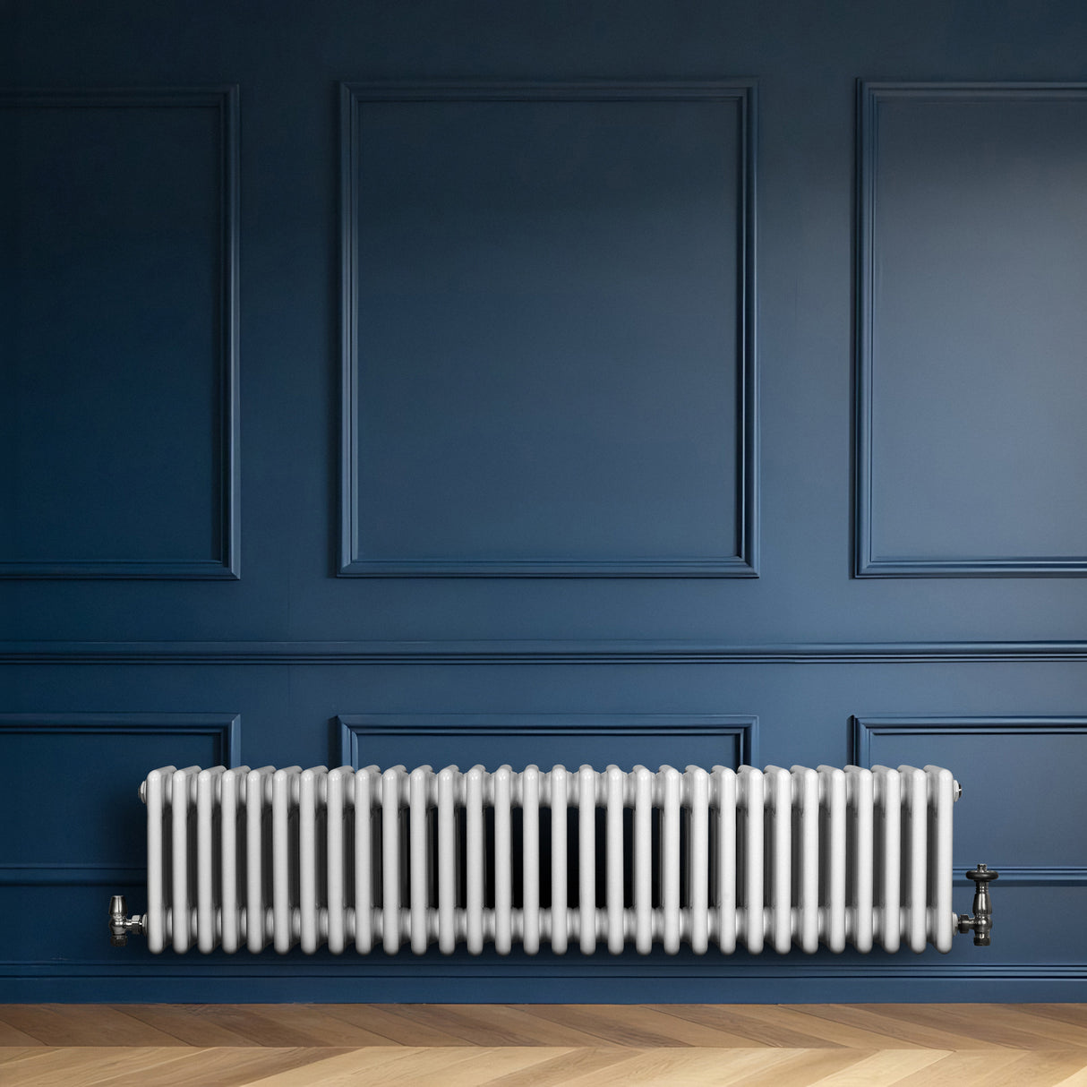 Radiatore tradizionale a 4 colonne, bianco lucido, installato su una parete blu scuro, con pavimento in legno chiaro