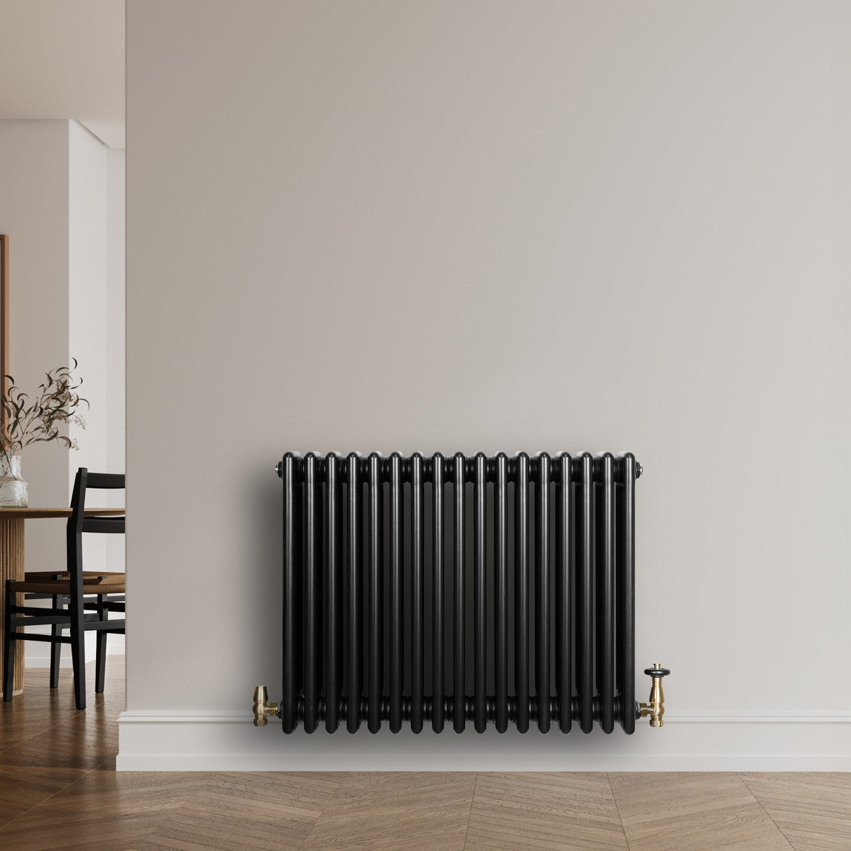 Radiatore tradizionale orizzontale a 4 colonne, colore nero lucido, installato su una parete bianca, con dettagli in ottone