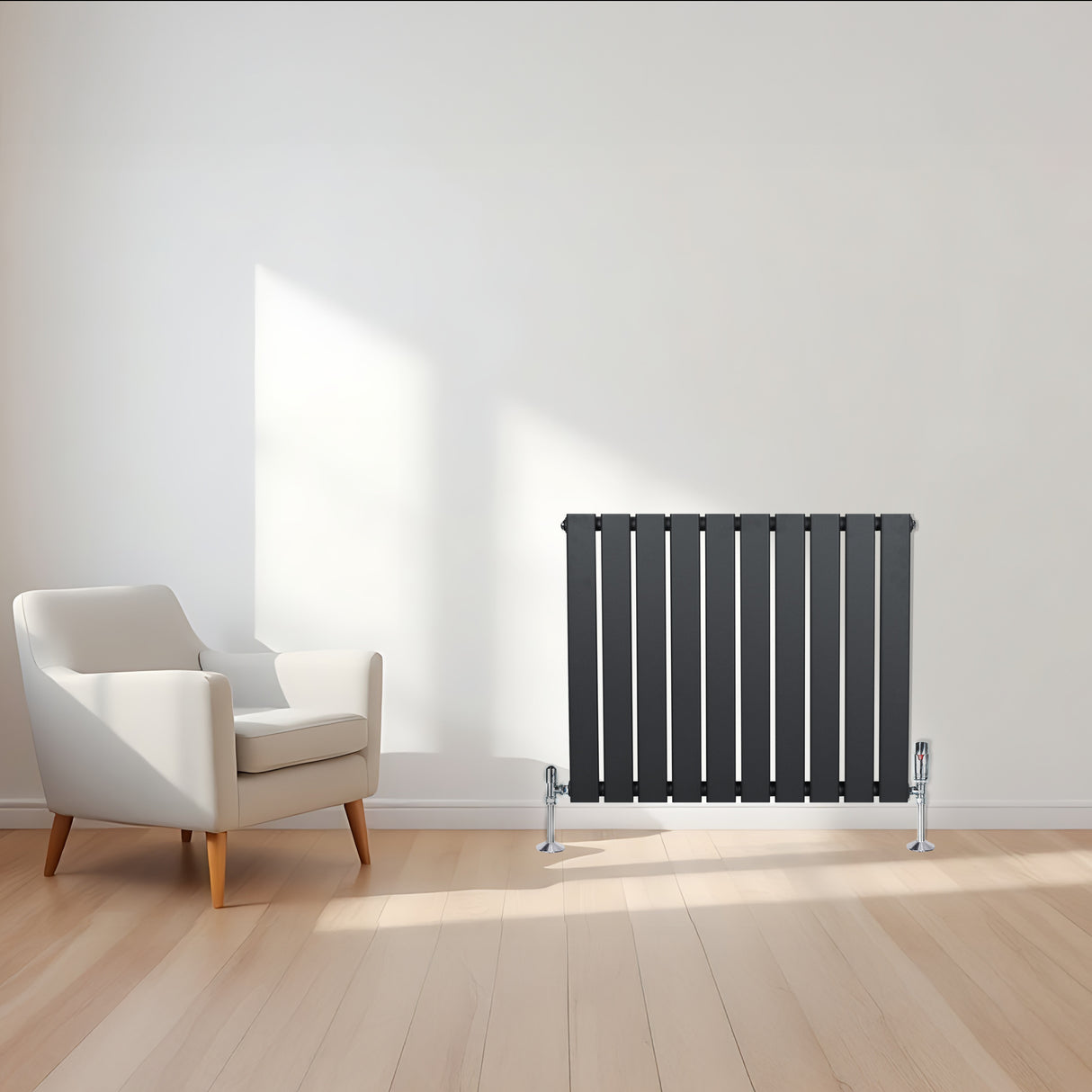 Radiatore piatto a colonna singola orizzontale antracite, con finitura liscia e linee moderne, posizionato accanto a una poltrona bianca in un ambiente luminoso
