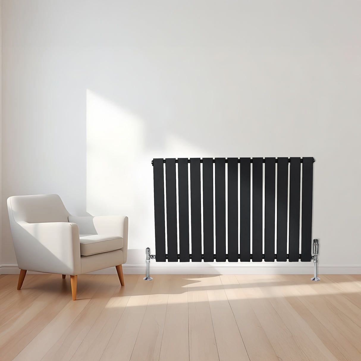 Radiatore piatto a colonna singola orizzontale nero, con finitura liscia e linee moderne, posizionato accanto a una poltrona bianca su pavimento in legno chiaro