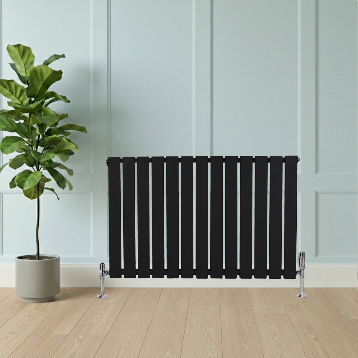 Radiatore piatto a colonna singola orizzontale 600 x 910 mm, finitura nera opaca, con design a listelli e supporti cromati, in ambiente moderno con pianta verde