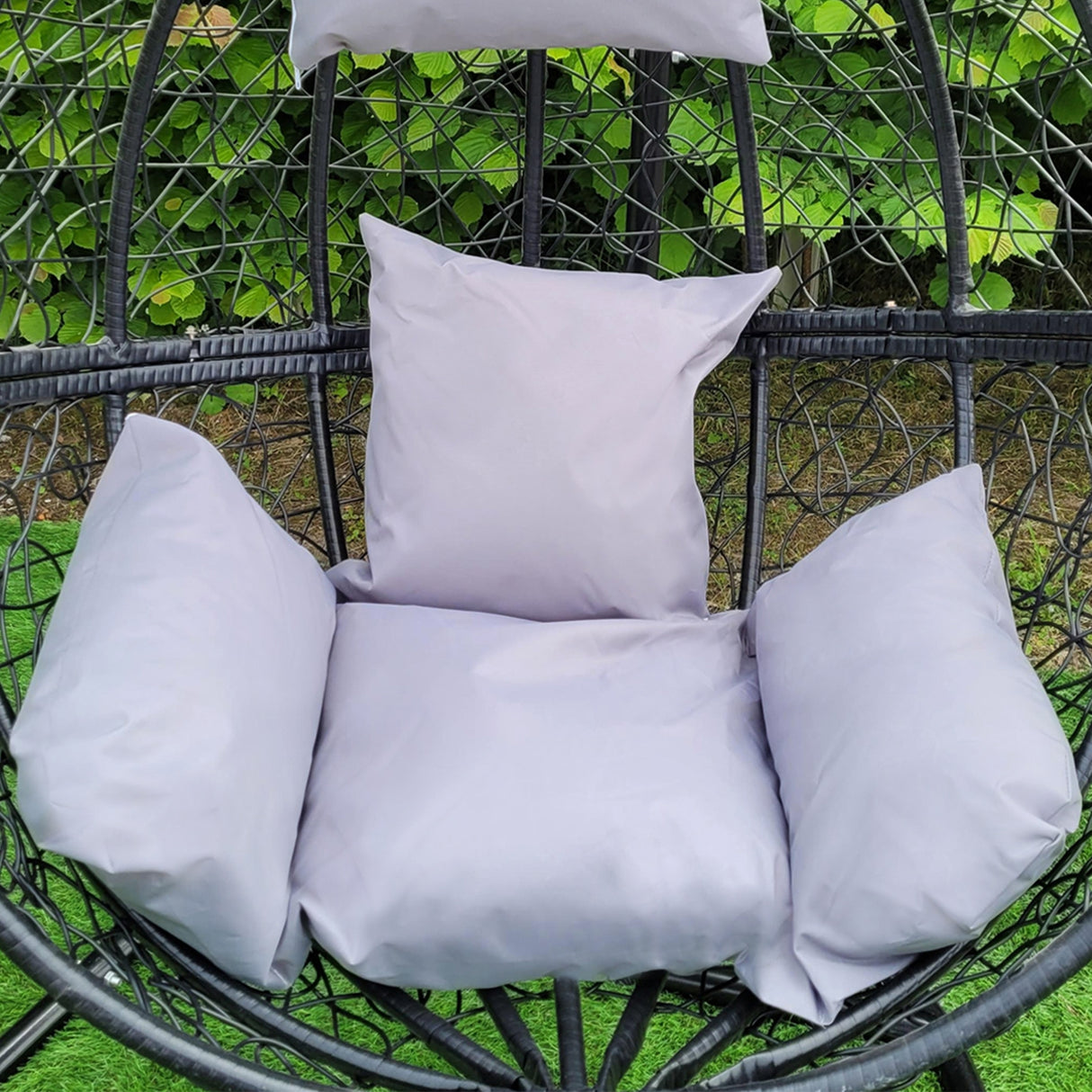 Sedia sospesa a uovo da giardino in rattan nero, con cuscini grigi morbidi, ideale per relax all'aperto e decorazione elegante