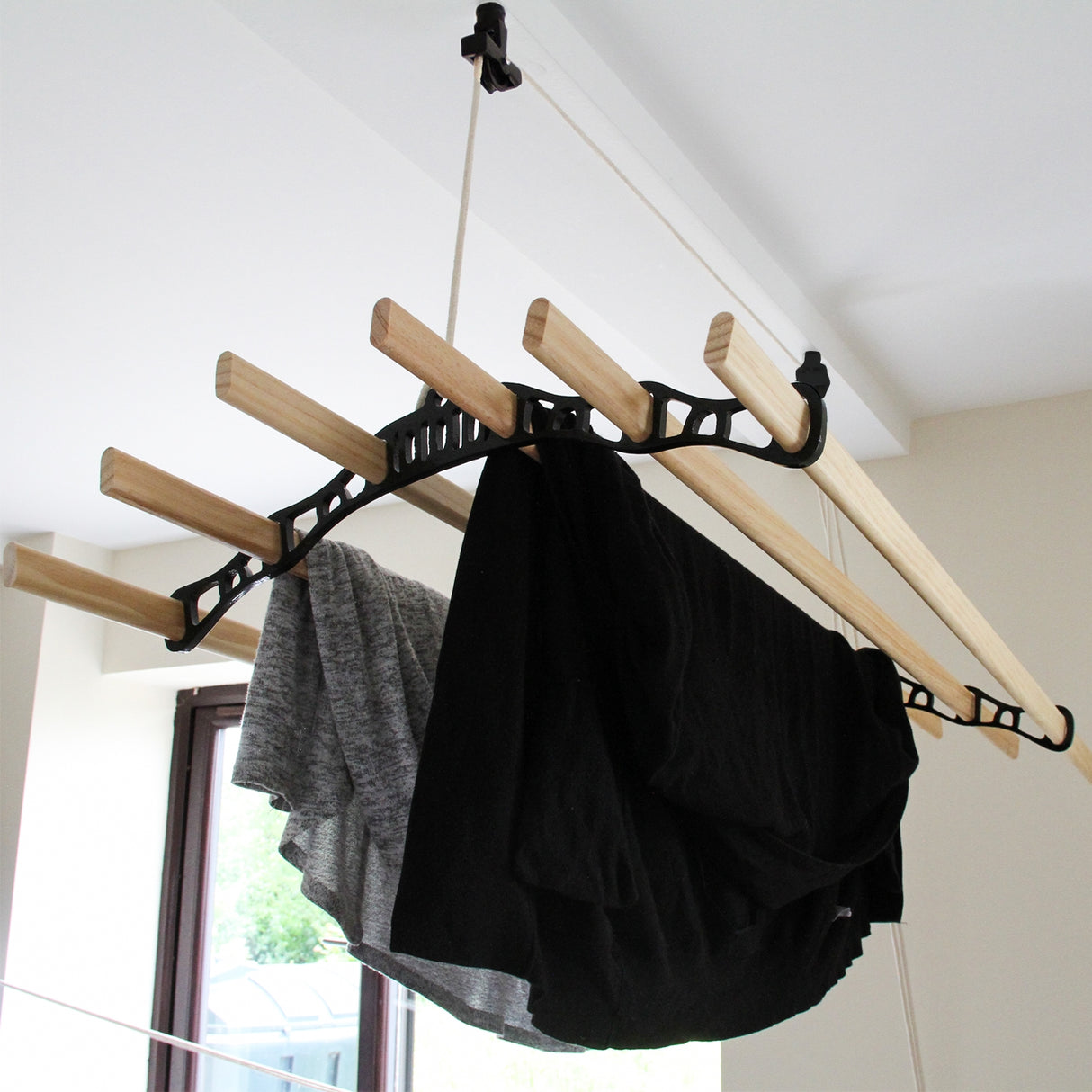 Stendibiancheria da soffitto nero con aste in legno, panni scuri appesi, design funzionale e moderno per spazi interni
