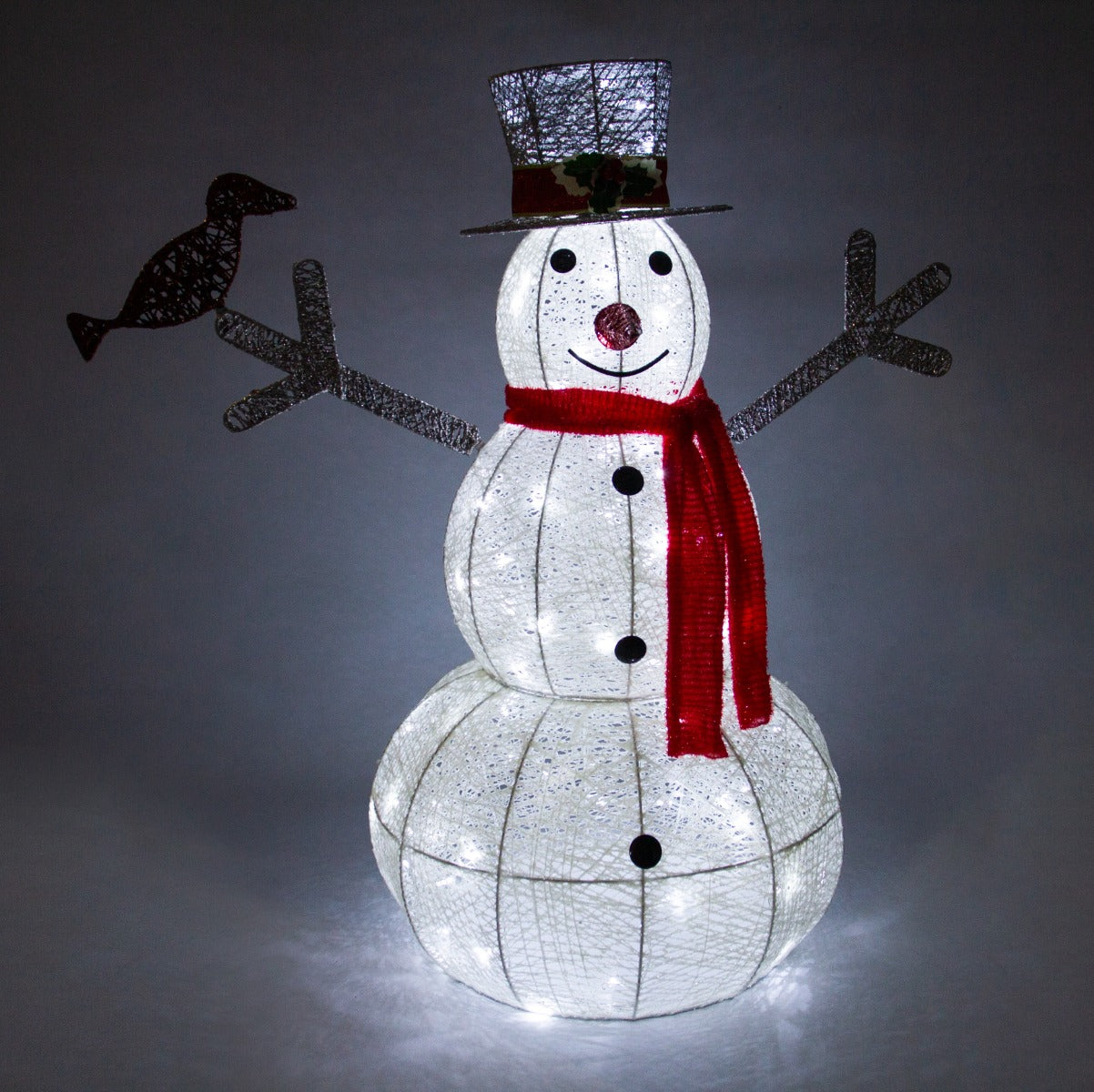 Pupazzo di neve luminoso con cappello a cilindro, sciarpa rossa e dettagli metallici, illuminato da luci bianche nel giardino natalizio