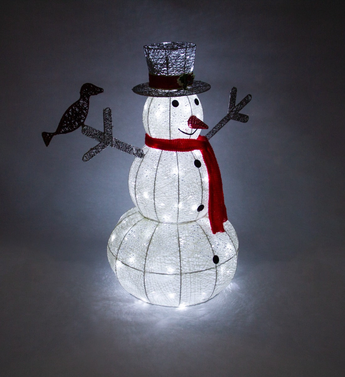 Pupazzo di neve luminoso con cappello a cilindro, sciarpa rossa e decorazioni, illuminato da luci bianche nel giardino natalizio