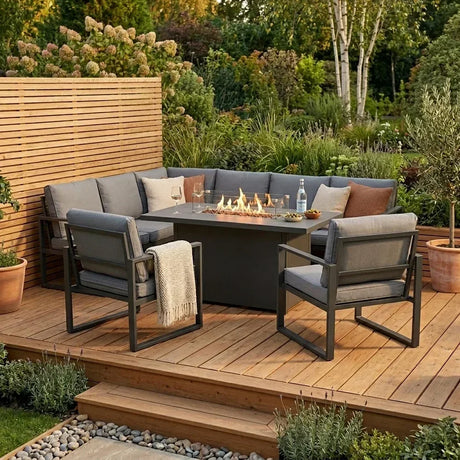 Set di mobili da giardino con braciere, cuscini grigi, tavolo centrale e piante verdi, ideale per serate all'aperto