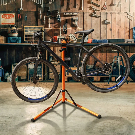 Cavalletto per riparazione biciclette arancione con bici nera montata, in un garage attrezzato con strumenti e attrezzi sullo sfondo