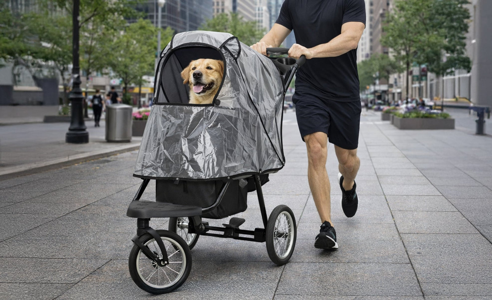 Carrozzina per cani grigia con un cane felice all'interno, spinta da un uomo su un marciapiede urbano, circondato da alberi e edifici