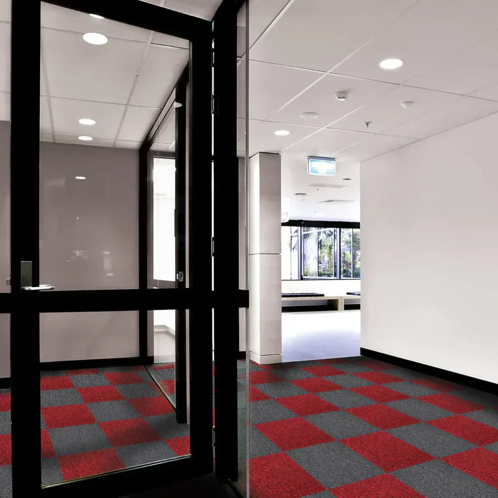 Pavimento in moquette con un motivo a scacchi rosso e grigio, in un ambiente moderno e luminoso con porte in vetro e pareti chiare