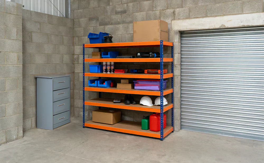 Scaffalatura arancione con ripiani in legno, contenitori blu, scatole di cartone e attrezzi, in un garage con pareti grigie