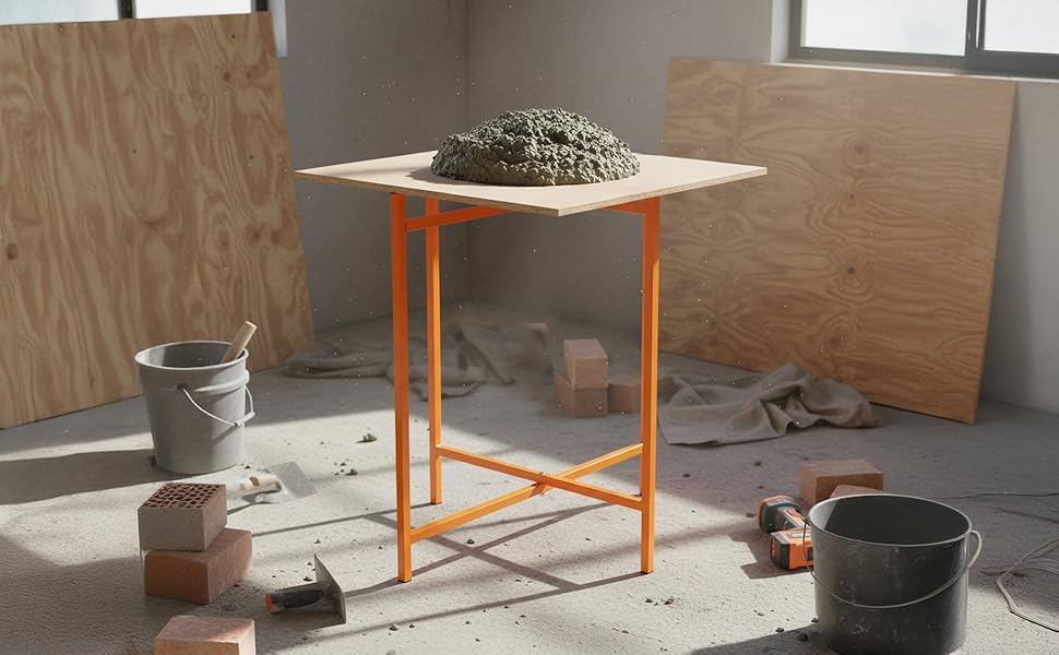 Cavalletto arancione per tavola da muratore con superficie in legno, sopra un impasto di cemento, circondato da mattoni e attrezzi da lavoro