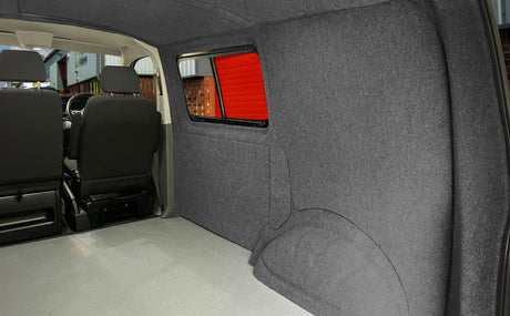 Rivestimento interno in tessuto grigio scuro per camper, con pareti morbide e spazio ben isolato, sedili neri visibili sullo sfondo