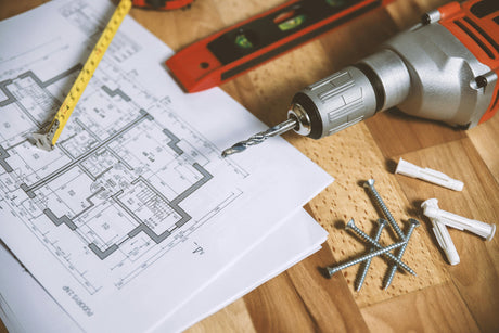 Piano di ristrutturazione su tavolo di legno con trapano elettrico, viti, tasselli e metro, strumenti per lavori di casa