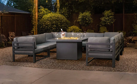Set di arredi da giardino in alluminio grigio con cuscini, tavolo centrale e illuminazione soffusa in un ambiente esterno elegante
