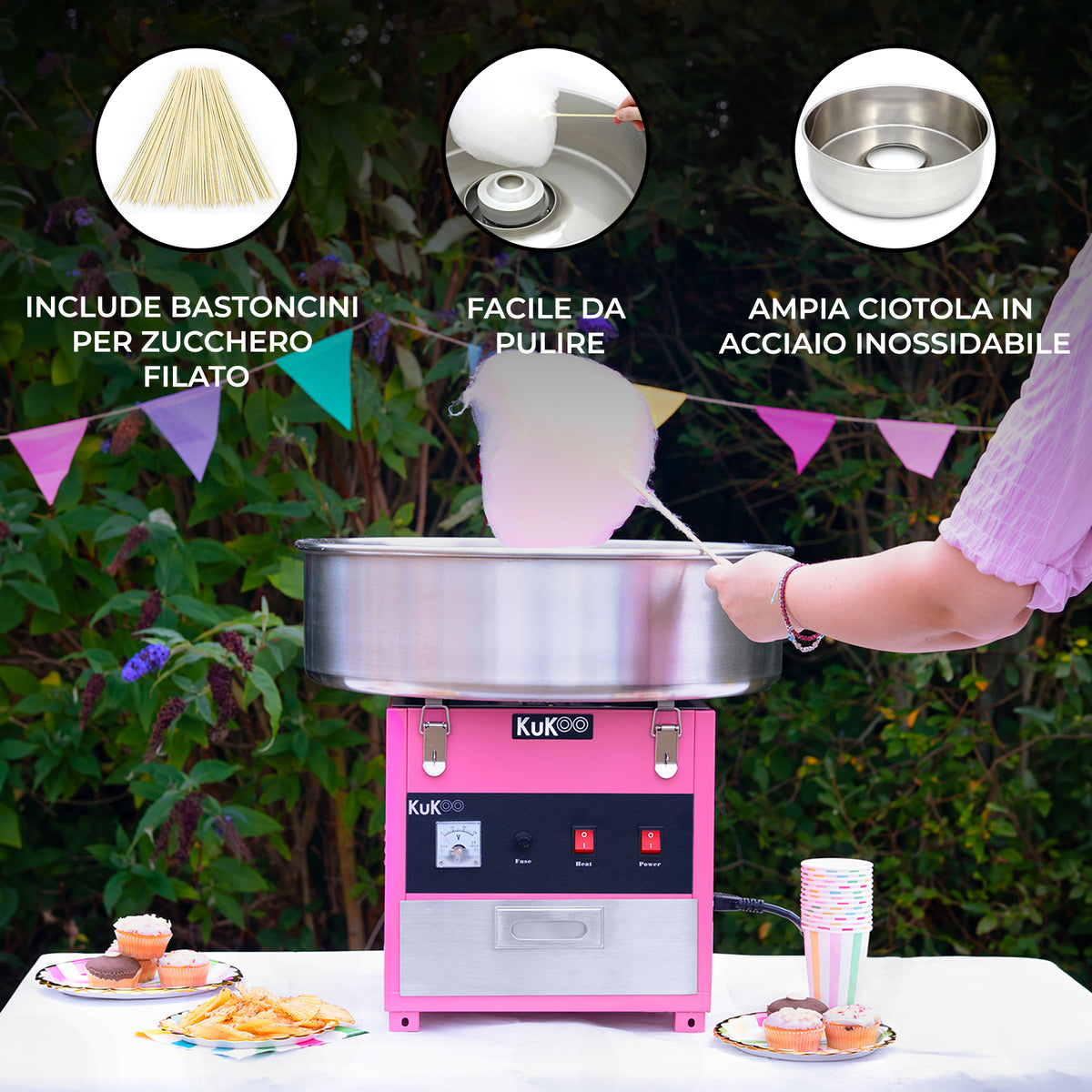 Macchina per zucchero filato KuKò, color rosa, con ciotola in acciaio inox e bastoncini inclusi, su sfondo festivo all'aperto