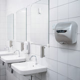 Asciugamani elettrici MaxBlast grigi, specchi e lavandini bianchi in un bagno moderno con piastrelle bianche lucide