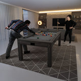 Tavolo multigioco 7-in-1 effetto legno grigio, con superficie grigia, utilizzato da due persone per giochi come biliardo e ping pong