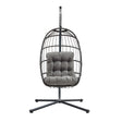 Poltrona sospesa a uovo in rattan nero, con struttura metallica e cuscino grigio imbottito, design moderno e accogliente