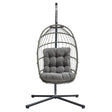 Poltrona sospesa a uovo in rattan grigio con cuscino imbottito, struttura nera, design moderno e accogliente per interni ed esterni