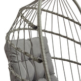 Poltrona sospesa a uovo in rattan grigio, con struttura metallica e cuscino grigio chiaro, design elegante e moderno