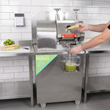 Pressa per canna da zucchero in acciaio inox, con un operatore che inserisce canne e raccoglie il succo verde in un contenitore trasparente