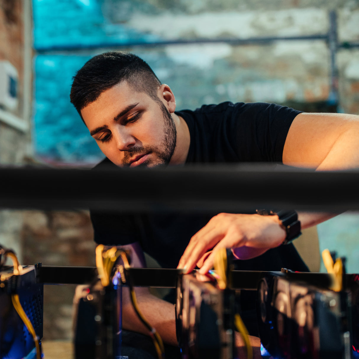 Tecnico che monta un telaio per impianto di mining da 6-8 GPU, con schede grafiche e cavi gialli in un ambiente industriale moderno