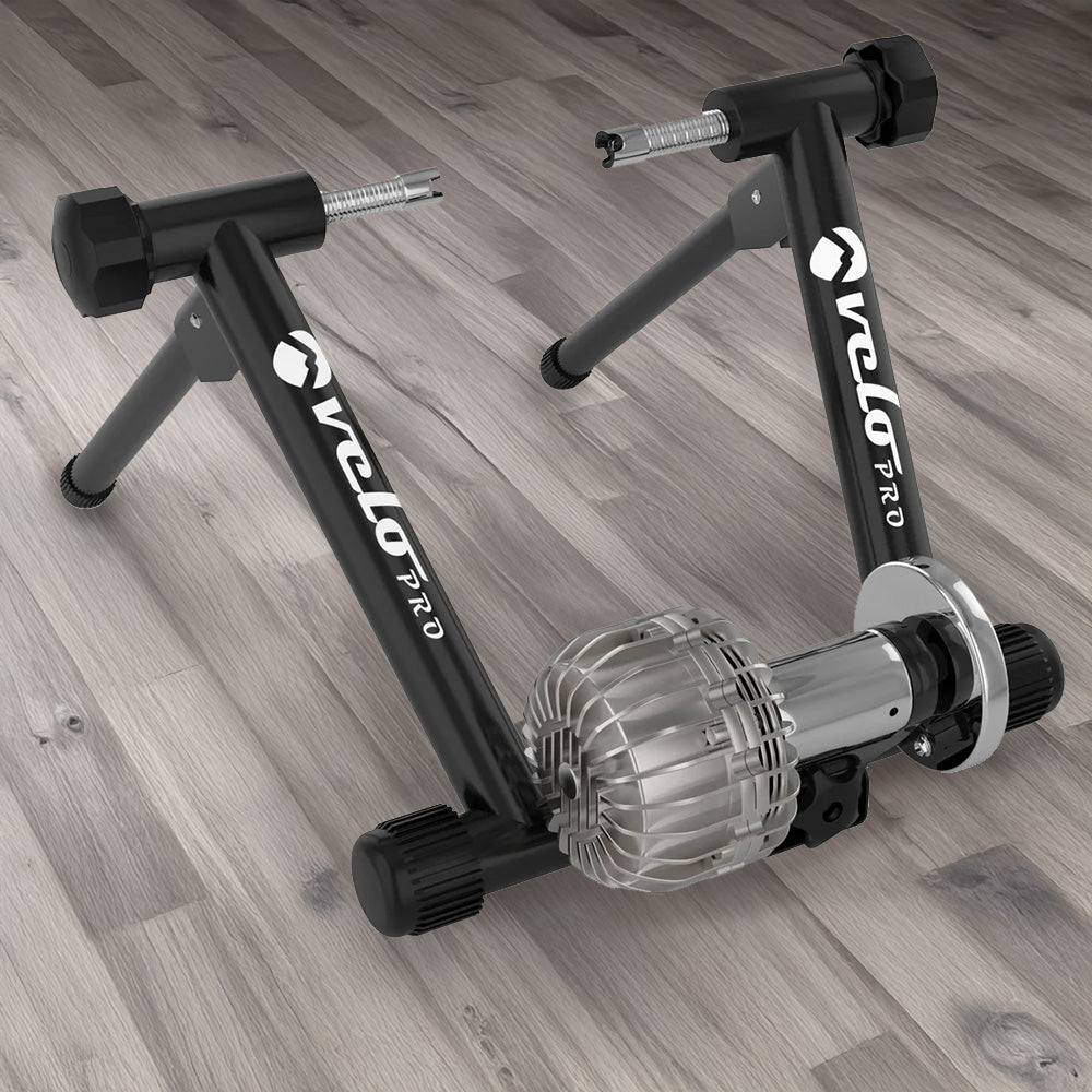 Rullo Fluido Velo Pro Nero con struttura nera e motore argentato, progettato per allenamenti indoor su pavimento in legno chiaro