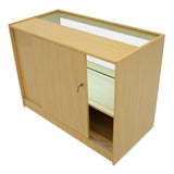 Bancone negozio in legno d'acero chiaro con ante scorrevoli, ripiano in vetro e spazio di stoccaggio sottostante, design moderno e funzionale