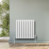 Radiatore ovale a colonna singola orizzontale bianco, con valvole, installato su parete grigia, in ambiente luminoso e naturale