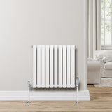 Radiatore ovale a colonna singola orizzontale bianco, con valvole cromate, installato su parete chiara in un ambiente luminoso e moderno