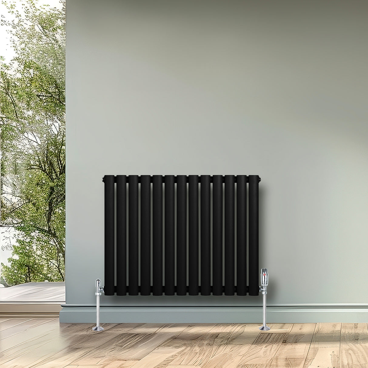 Radiatore ovale a colonna singola orizzontale nero, con finitura liscia e valvole, posizionato su una parete chiara in un ambiente luminoso