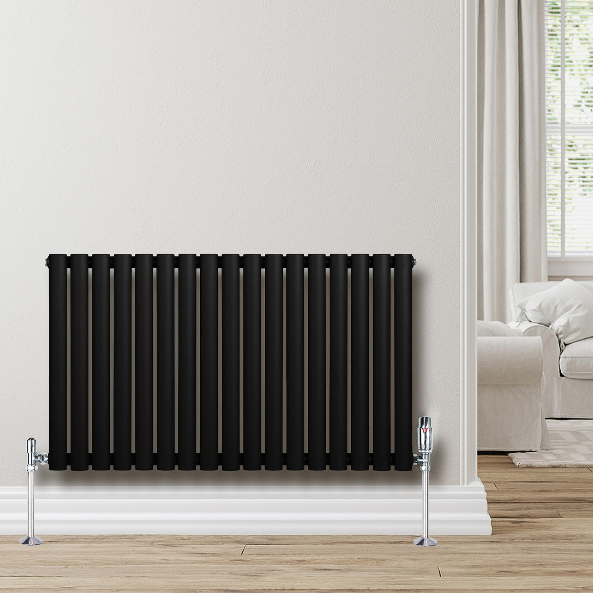 Radiatore ovale a colonna singola orizzontale, 600 x 1020 mm, colore nero opaco, con valvole cromate, posizionato su parete chiara