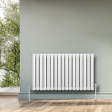 Radiatore ovale a colonna singola orizzontale bianco, con finitura liscia e valvole, posizionato su un pavimento in legno chiaro