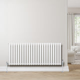 Radiatore ovale a colonna singola orizzontale bianco, con finitura liscia e valvole, posizionato su una parete chiara in un ambiente luminoso