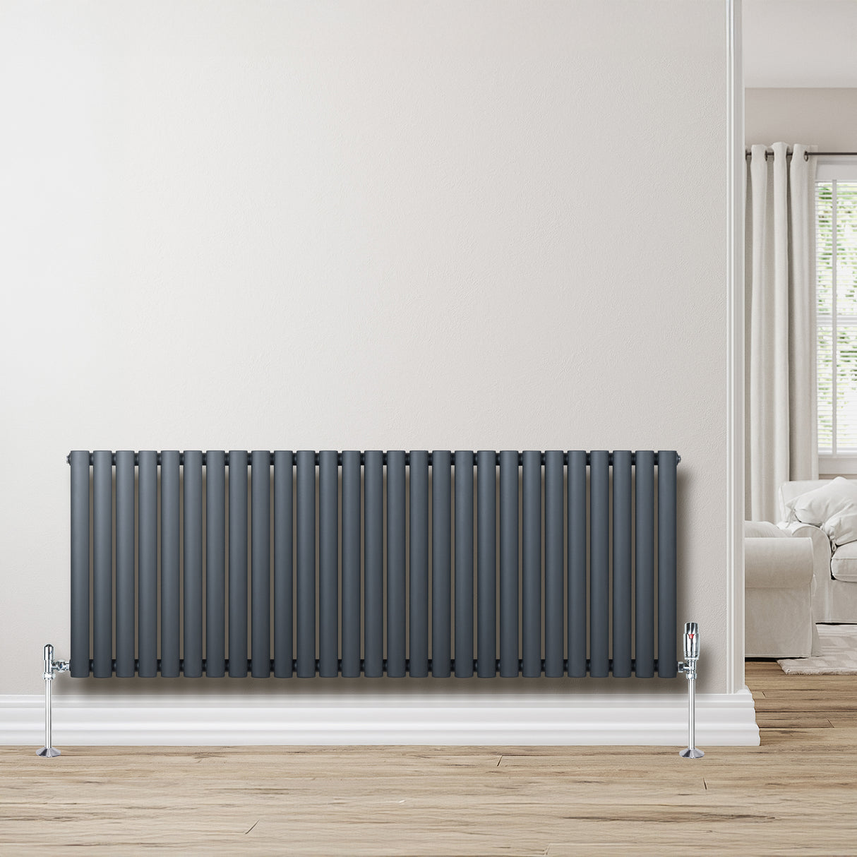 Radiatore ovale a colonna singola orizzontale antracite, con finitura liscia e valvole, posizionato su un pavimento in legno chiaro