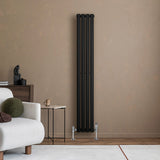 Radiatore ovale a colonna singola verticale nero, 1600 x 240 mm, con valvole, elegante design moderno su parete beige in ambiente minimalista