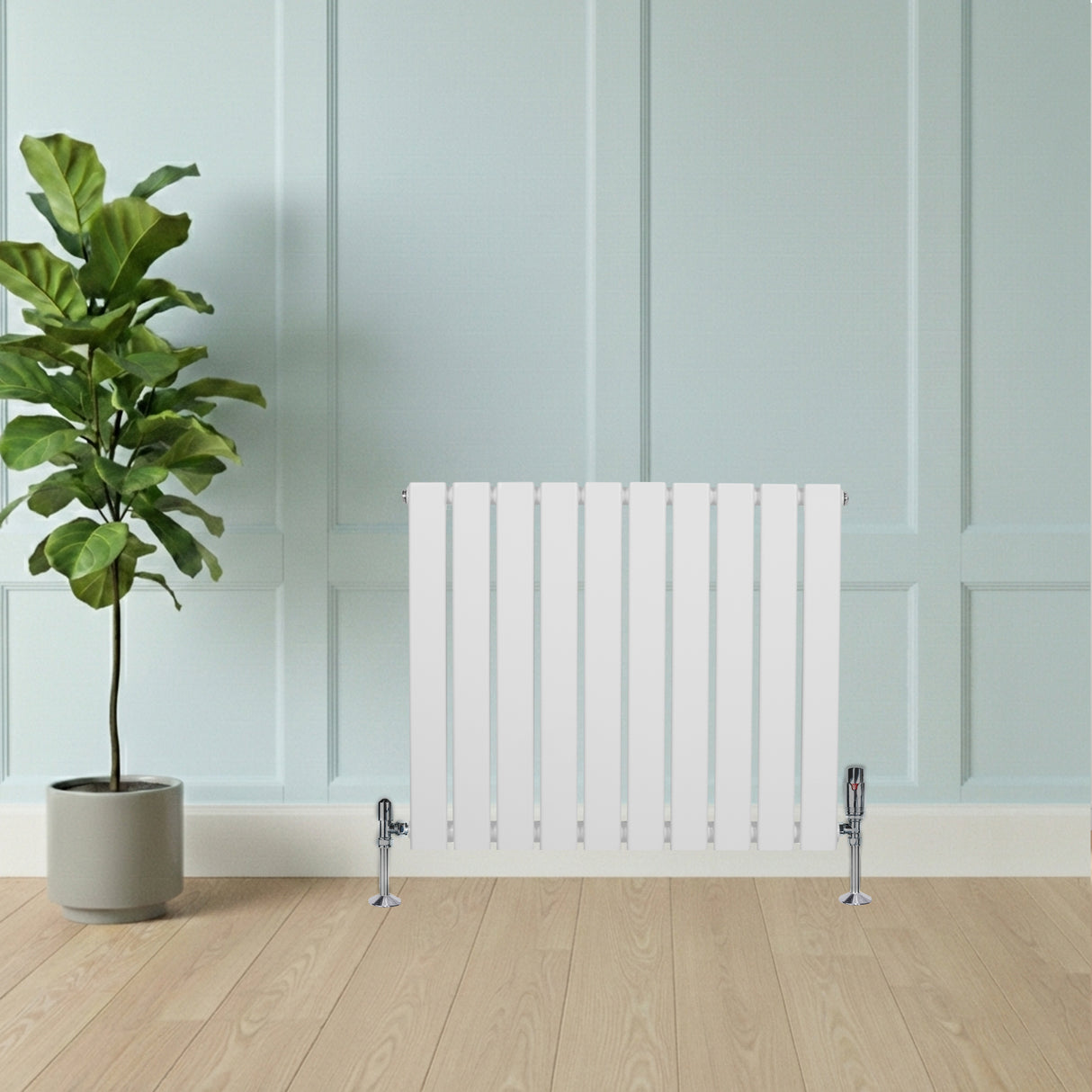 Radiatore piatto monocolonna bianco con finitura liscia, installato su parete chiara, accanto a una pianta verde in vaso