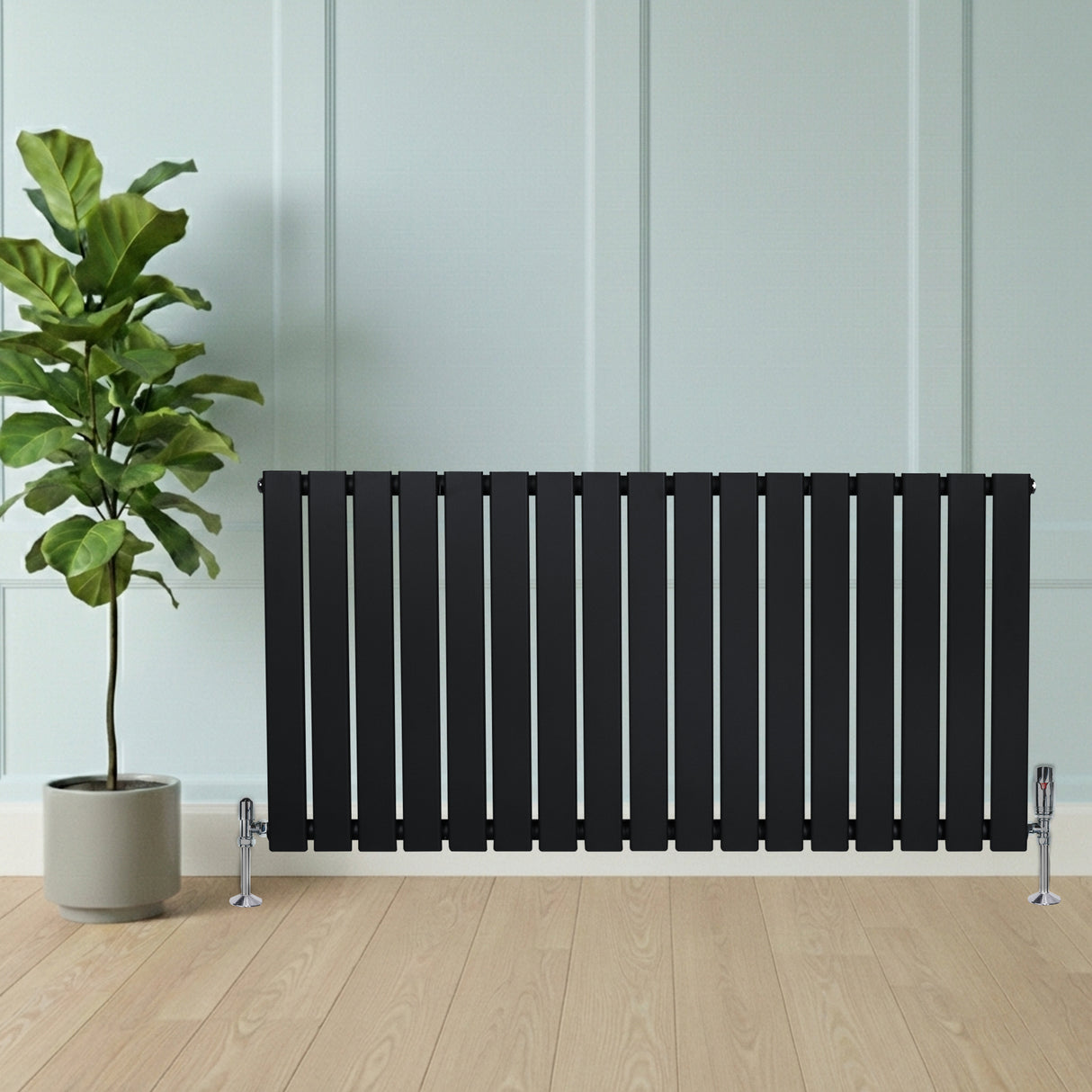 Radiatore piatto monocolonna nero, 600 x 1190 mm, con finitura liscia e valvole, posizionato accanto a una pianta in vaso su pavimento in legno