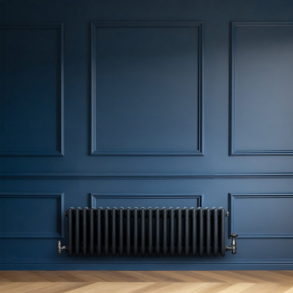 Radiatore tradizionale a 4 colonne in grigio antracite, installato su una parete blu scuro, con finitura liscia e dettagli eleganti
