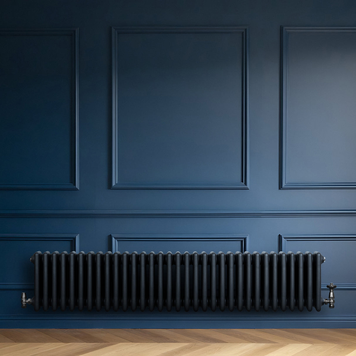 Radiatore tradizionale a 4 colonne in grigio antracite, lungo e rettangolare, con finitura liscia e valvole laterali, su sfondo blu scuro
