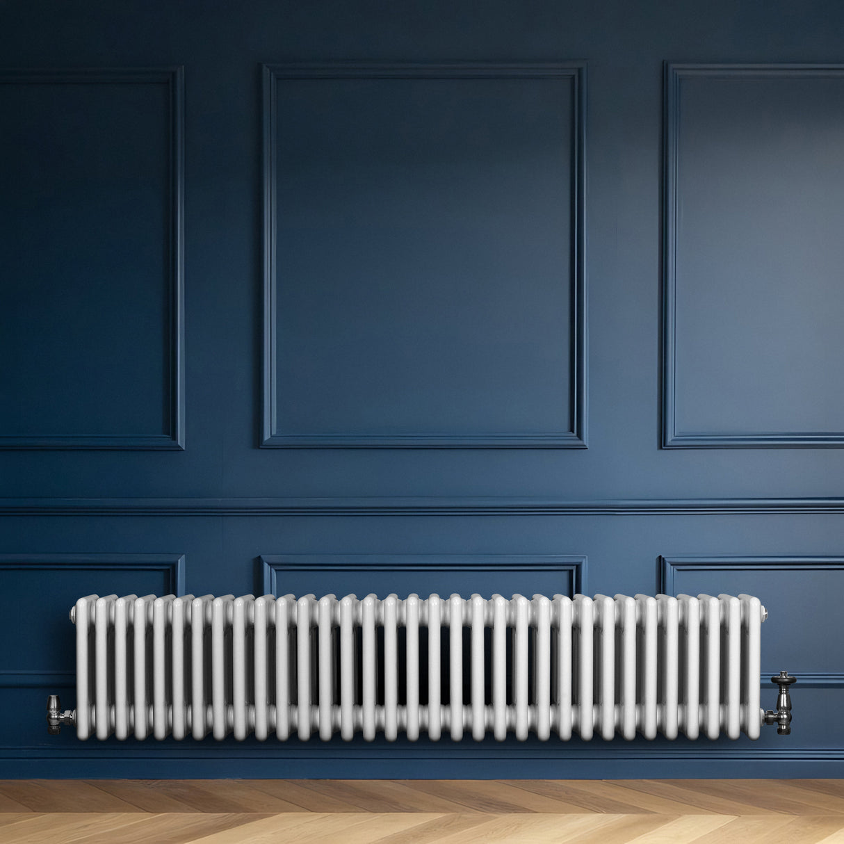 Radiatore tradizionale a 4 colonne, bianco lucido, installato su una parete blu scuro, con pavimento in legno chiaro elegante