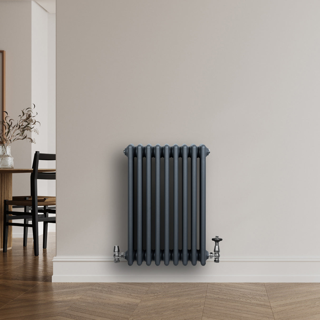 Radiatore tradizionale a 4 colonne, grigio antracite, installato su parete bianca, con valvole metalliche lucide e design elegante