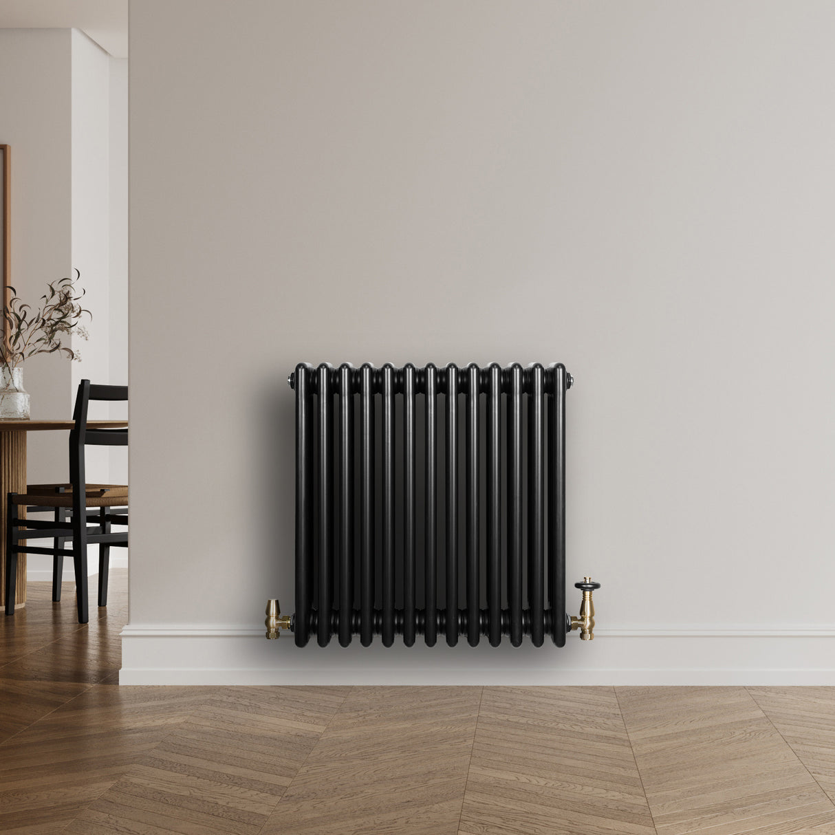Radiatore tradizionale a 4 colonne, finitura nera lucida, installato su parete bianca, con valvole dorate e design elegante
