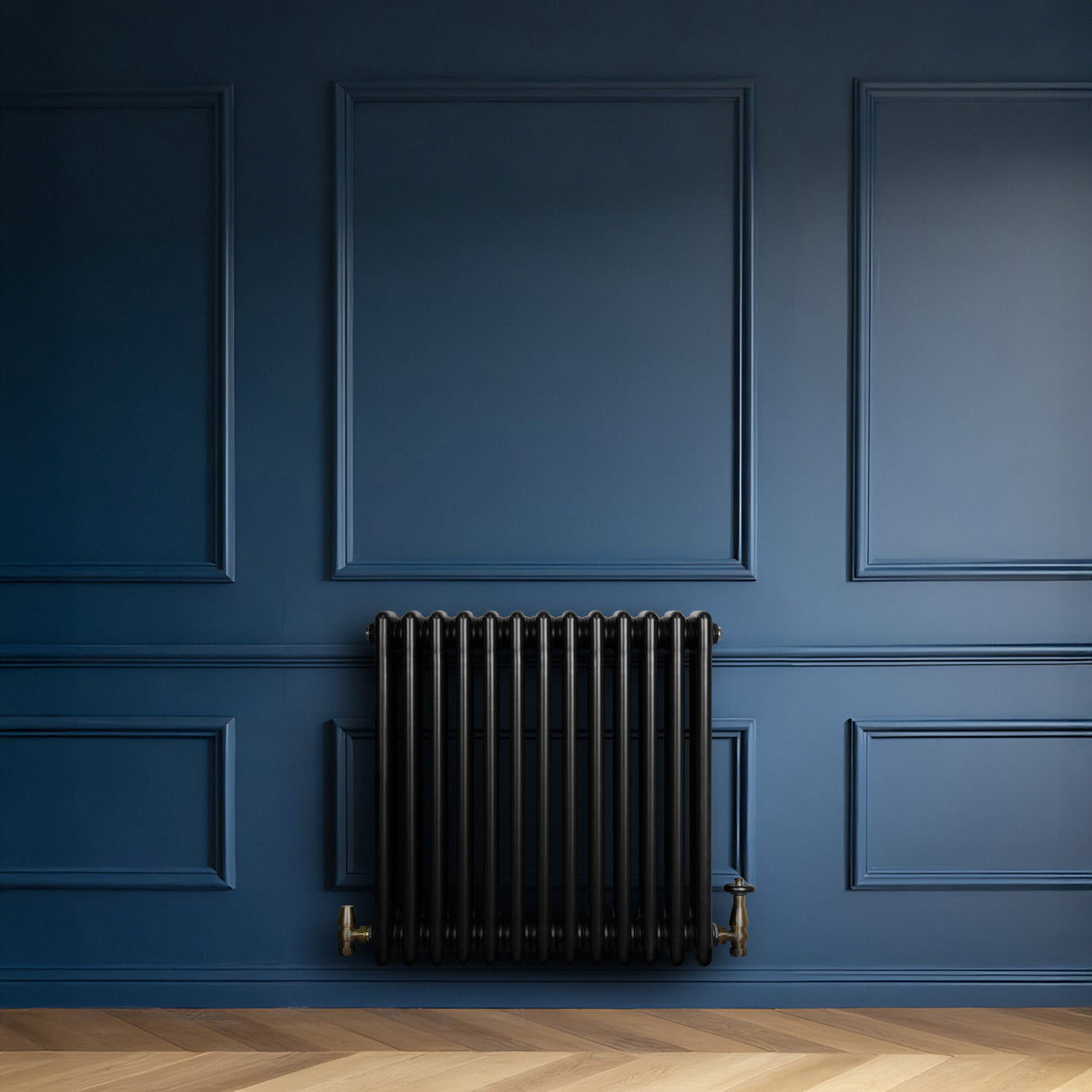 Radiatore tradizionale a 4 colonne, nero lucido, con valvole, posizionato su una parete blu scuro, su pavimento in legno chiaro