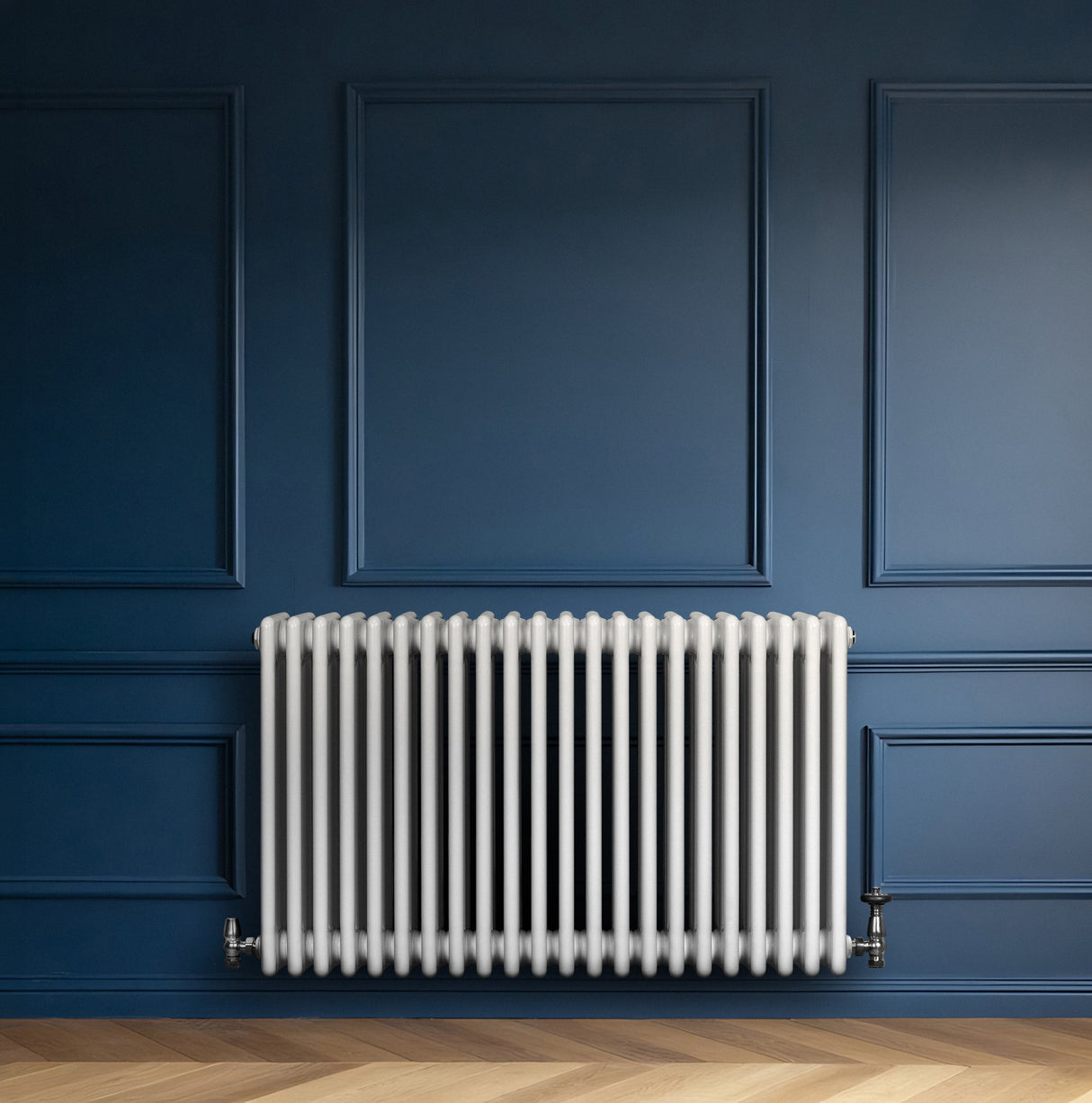 Radiatore tradizionale bianco a 4 colonne orizzontali, installato su una parete blu, con valvole metalliche lucide e finitura liscia