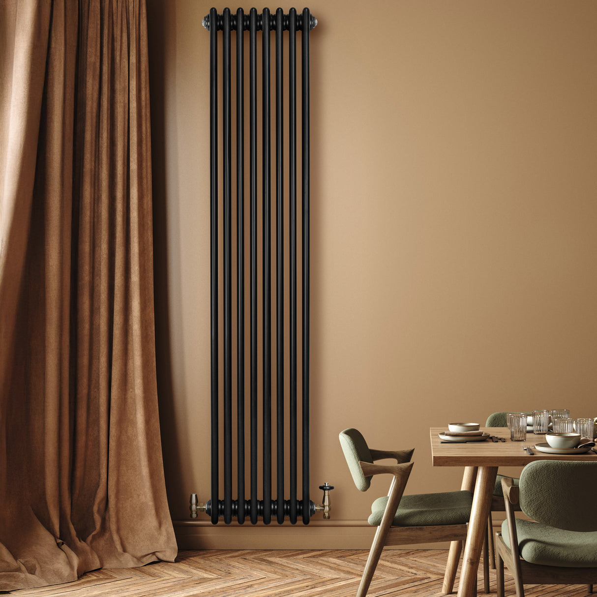 Radiatore tradizionale verticale a 4 colonne, finitura nera opaca, installato su parete beige, accanto a tavolo e sedie verdi