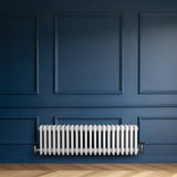 Radiatore tradizionale a 4 colonne, bianco lucido, installato su una parete blu scuro, con dettagli eleganti e valvole in metallo